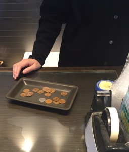 In most establishments in Japan, when you check out, trays are used for the money. They put the empty tray there and total your purchases and tell you the amount due. You put it in the tray and they pick it up. They put your change in the tray and pass it back.
